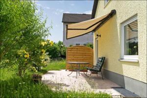 a patio with a table and chairs next to a building at Wiesenhaus, Ferienhaus in Manderscheid