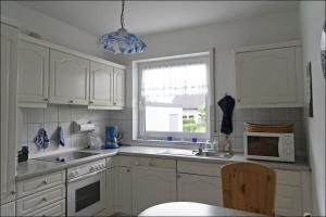 a kitchen with white cabinets and a sink and a window at Wiesenhaus, Ferienhaus in Manderscheid