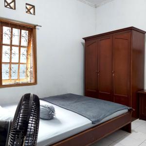 a bedroom with a bed and a wooden cabinet at Villa Ananda 1, 3 KT Kolam Renang, Karaoke Biliar in Cisarua