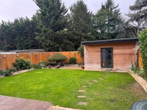 a backyard with a wooden fence and a green lawn at Hidden Gem in Foots Cray