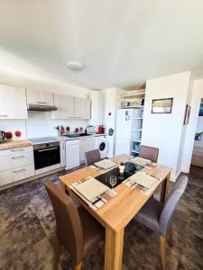 a kitchen with a wooden dining table and chairs at Chez Jiri - Piscine, Balcon vue Alpes, Spacieux T2 in Gex