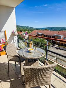 a table and chairs on a balcony with a view at Chez Jiri - Piscine, Balcon vue Alpes, Spacieux T2 in Gex