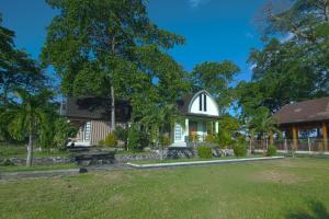 a building with a grassy yard in front of it at Pohon Purba Resort & Restaurant in Pulau Lebur
