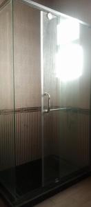 a shower stall with a glass door with a faucet at Rivana Inn - ريفانا in ‘Izbat an Nāmūs
