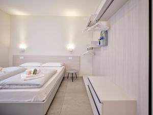 a white bedroom with two beds and a table at Pegaso Civico2 in Garda