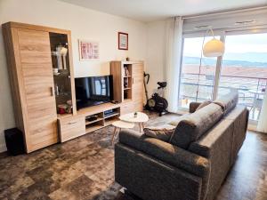 a living room with a couch and a television at Chez Jiri - Piscine, Balcon vue Alpes, Spacieux T2 in Gex