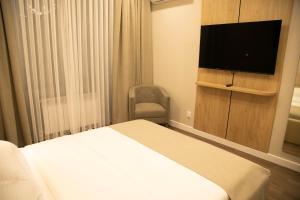 a hotel room with a bed and a flat screen tv at Aristocrat Hotel in Kapchagay