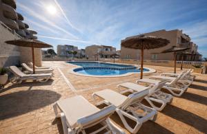 a group of chairs and umbrellas next to a pool at Casa Claudia&Simon in Santa Pola
