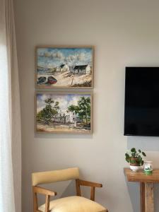 two paintings on a wall with a chair and a television at Whale Coast Luxury Suites in Hermanus