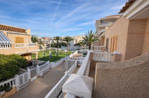 a balcony with a bench and buildings and palm trees at Casa Claudia&Simon in Santa Pola
