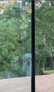 a glass window with a view of a forest at Pousada Refúgio Arauca in Campo Alegre