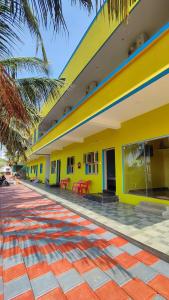 a yellow building with red tables in front of it at Amirtham Holiday Home in Kovakulam