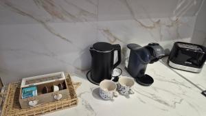 a counter with a coffee maker and a basket of cups at Silver Marina Residence in Veliko Gradište