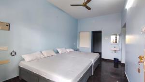 a bedroom with a white bed with a ceiling fan at Amirtham Holiday Home in Kovakulam +6 photos