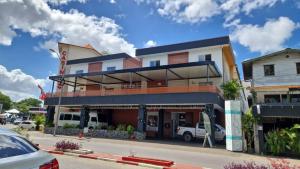 a building on a street with cars parked in a parking lot at Queens Hotel in Paramaribo