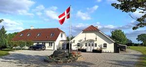 eine Flagge vor einem weißen Haus mit einer Flagge in der Unterkunft Brændekilde Bed & Breakfast in Ullerslev