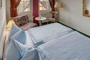 a bedroom with a large bed and a chair at Hotel zum Kater in Rostock