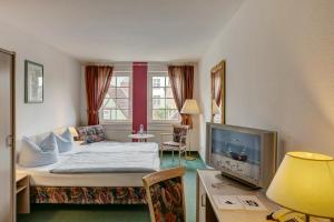 a hotel room with a bed and a tv at Hotel zum Kater in Rostock