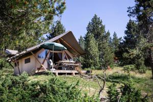 a small tent with a table and an umbrella at Huttopia Font Romeu in Font-Romeu