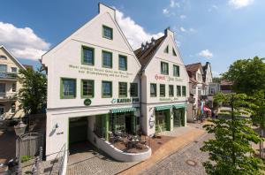 a large white building with green windows on a street at Hotel zum Kater in Rostock