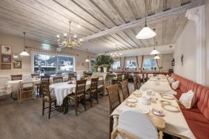a restaurant with white tables and chairs and a red couch at Hotel Garni Keil in Kleinarl