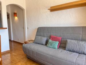 a gray couch with two colorful pillows on it at Basic Comfort Studio Poblat tipic 0168 in Empuriabrava