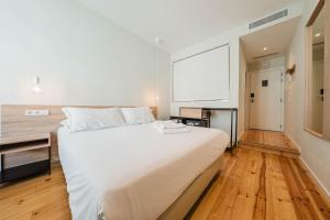 a bedroom with a large white bed and a desk at Liberator Rossio in Lisbon +58 photos