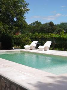 two white chairs and a table next to a swimming pool at Finca La Marta - El Cortijo Wine Lodge in Capilla del Monte