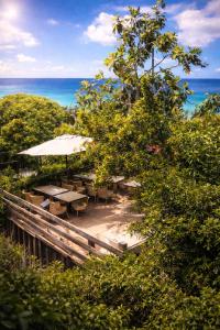a patio with tables and umbrellas and the ocean at Tidododesiles in Bouillante