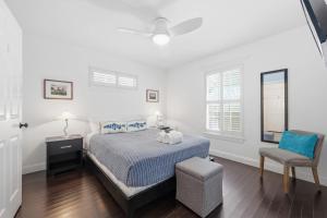 a white bedroom with a bed and a chair at Weeden Cottage in St. Augustine