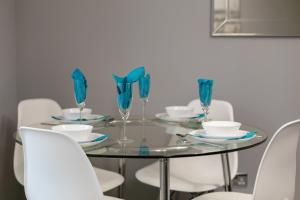 a dining room table with blue glasses and white chairs at Forbes Retreat - Donnini Apartments in Ayr +7 photos