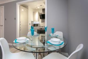 a dining room with a glass table and white chairs at Forbes Retreat - Donnini Apartments in Ayr