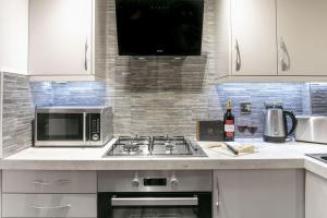 a kitchen with a stove and a microwave at Forbes Retreat - Donnini Apartments in Ayr