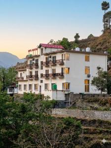 a large white building on a hill with trees at Hotel Anantam Residency in Uttarkāshi