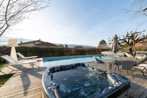 a hot tub on a deck next to a swimming pool at Villa Crysaële in Menthon-Saint-Bernard