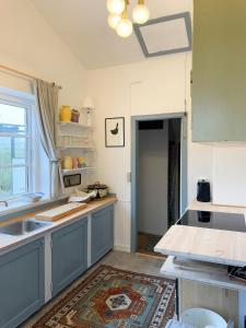a kitchen with blue cabinets and a sink and a window at Thatched Cottage Near Dronningmølle Beach in Dronningmølle