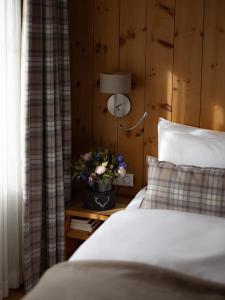 a bedroom with a bed and a lamp and flowers at Hotel Adula in Flims