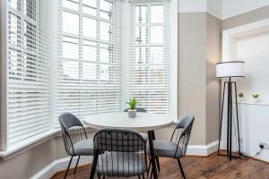 a dining room with a table and chairs in front of windows at Main Street View - Donnini Apartments in Prestwick