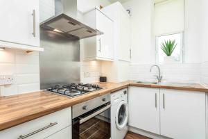 a white kitchen with a stove and a sink at Main Street View - Donnini Apartments in Prestwick