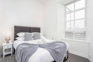 a white bedroom with a large bed and a window at Main Street View - Donnini Apartments in Prestwick +15 photos