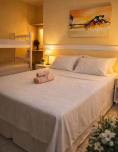 a large white bed with a teddy bear on it at GrandMaré Hotel in Peruíbe +22 photos