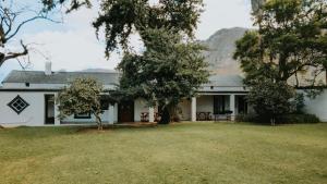 a white house with a yard and trees at Oregon House in Riebeek-Wes