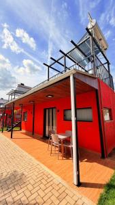 a red building with a table and chairs on a deck at Chalés - Aquabeat in Sao Jose da Lapa