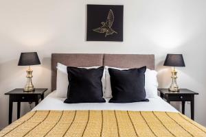 a bedroom with a bed with black pillows and two lamps at Walker Suite No53 - Donnini Apartments in Kilmarnock