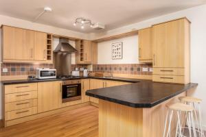 a kitchen with wooden cabinets and a black counter top at Walker Suite No53 - Donnini Apartments in Kilmarnock +4 photos