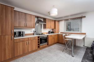a kitchen with wooden cabinets and a table in it at Walker Suite No73 - Donnini Apartments in Kilmarnock