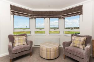 two chairs and a table in a room with windows at Links View - Donnini Deluxe in Prestwick