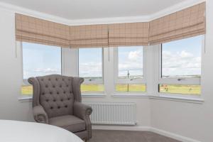 a bedroom with a chair in front of windows at Links View - Donnini Deluxe in Prestwick