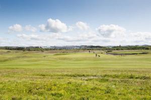 a golf course with people playing on a green at Links View - Donnini Deluxe in Prestwick