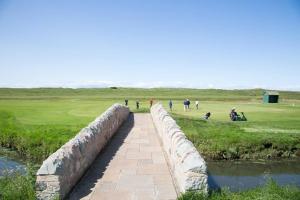 a stone bridge over a river with people playing golf at Links View - Donnini Deluxe in Prestwick +12 photos
